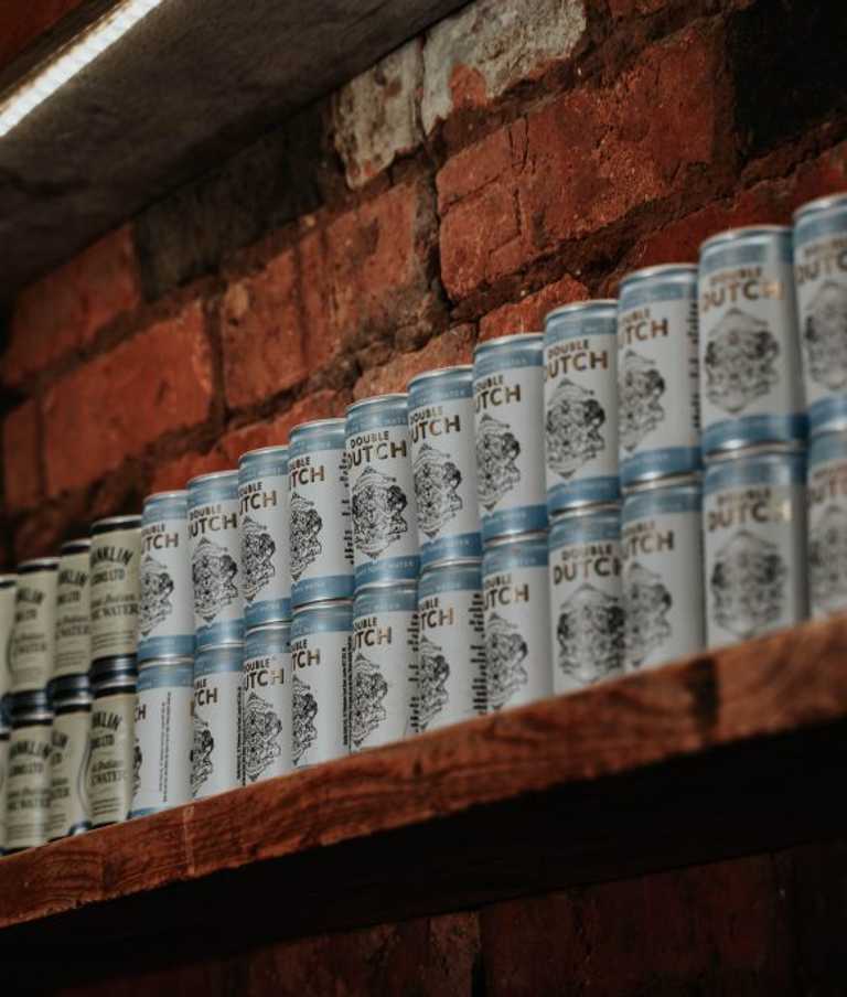 Tonic water cans stack on an exposed brick wall